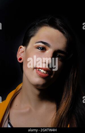 Young beautiful hispanic transgender woman against black background Stock Photo