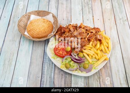 Turkish kebab dish menu of roasted chicken meat with salad of lettuce, tomato, green olives and red onion garnished with fried potatoes and grilled pi Stock Photo