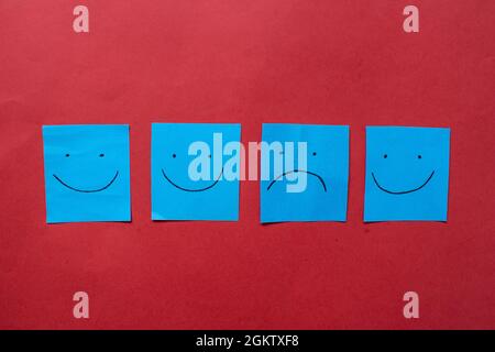 Hand drawn faces on stickers. One sad face among happy faces. Exclusion,discrimination,  difference concept. Stock Photo