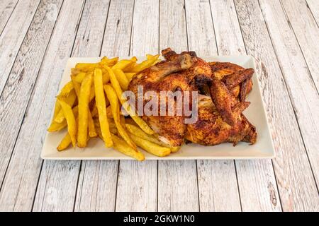 Tray of chopped large roast chicken and side of homemade potato chips on light table Stock Photo