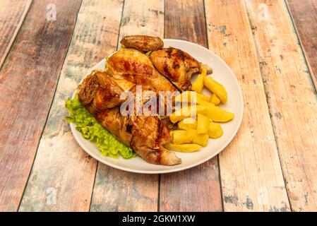 Baked whole roasted chicken halves with homemade potato chips on round white plate Stock Photo