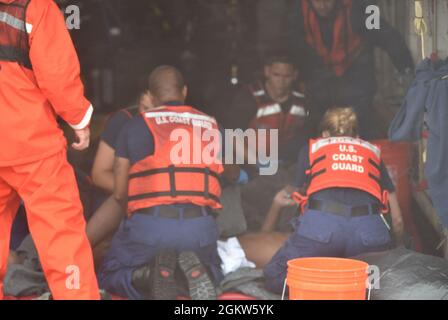 Crewmembers aboard the Coast Guard Cutter Thetis provide medical attention people rescued from the water approximately 32 miles southeast of Key West, Florida, July 7, 2021. The Coast Guard and a good Samaritan rescued 13 people from the water. Stock Photo