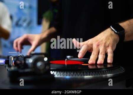 Hip hop dj scratching vinyl records on stage. Professional disc jockey scratches analog record with turn table and sound mixer devices Stock Photo