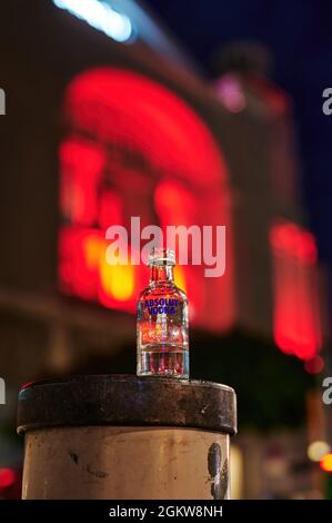 Berlin, Germany - June 23, 2021: Night shot of a small bottle of vodka that was left on a bollard as garbage. Stock Photo