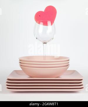 Pink plates and a pink cleaning sponge in a shape of a heart Stock Photo