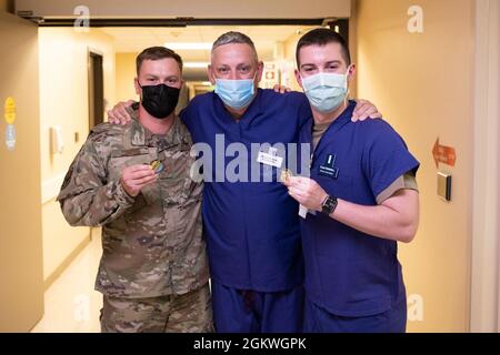 U.S. Air Force Col. Corey Simmons, center, 60th Air Mobility Wing commander, recognizes Senior Airman Timothy Perrine, left, 60th Inpatient Therapeutic Squadron critical care technician, and 1st Lt. Chad Swindell, right, 60th Medical Group critical care nurse, with a 60th AMW coin during leadership rounds July 9, 2021, at Travis Air Force Base, California. The Leadership Rounds program provides 60th AMW leadership an opportunity to interact with Airmen and receive a detailed view of each mission performed at Travis AFB. Stock Photo