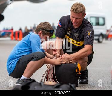 Sgt. 1st Class Houston Creech, member of the U.S. Army Parachute Team, packs his parachute with the help of a spectator after a free fall demonstration in Dayton, Ohio, July 10, 2021. The U.S. Army Parachute Team performs aerial demonstrations in support of recruiting. Stock Photo