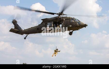 Staff Sgt. Timothy Thomas, a flight paramedic assigned to 3rd Forward Support Medical Platoon, 2nd General Support Aviation Battalion, 1st Combat Aviation Brigade, Task Force Nightmare, is lowered down on a hoist in order to retrieve a simulated patient during a MEDEVAC training exercise at Novo Selo Training Area, Bulgaria on July 14, 2021. Total readiness encompasses training, equipment and personnel and maintaining that readiness reassures our allies and deters potential adversaries. Stock Photo