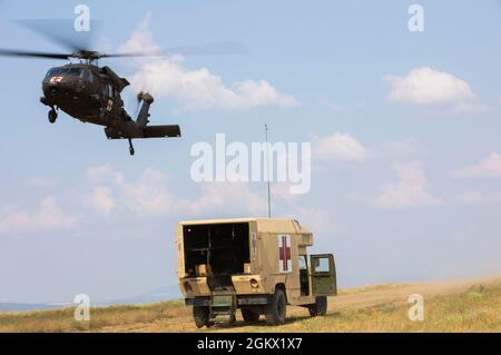 A HH-60 Blackhawk assigned to 3rd Forward Support Medical Platoon, 2nd General Support Aviation Battalion, 1st Combat Aviation Brigade, Task Force Nightmare, approaches a field liter ambulance as it prepares to execute a hoist extraction MEDEVAC in simulated training at Novo Selo Training Area, Bulgaria on July 14, 2021. U.S. Army Europe and Africa will ensure the consistent availability of combat-credible U.S. Army forces in support of our allies and partners and the stability and security of Europe. Stock Photo