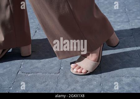 Beautiful woman feet after pedicure wearing high heel suede sandals and retro style bell-bottoms flare pants. Confident step forward. Stock Photo