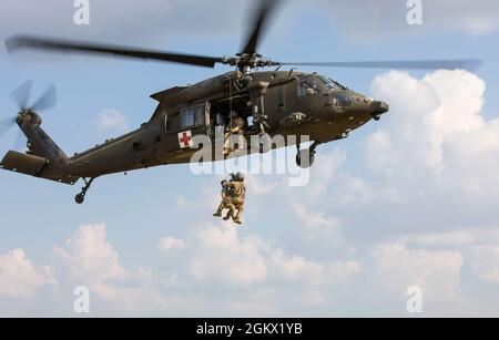 Staff Sgt. Timothy Thomas, a flight paramedic assigned to 3rd Forward Support Medical Platoon, 2nd General Support Aviation Battalion, 1st Combat Aviation Brigade, Task Force Nightmare, retrieves a patient using a hoist during a multi-day MEDEVAC training exercise at Novo Selo Training Area, Bulgaria on July 14, 2021. Total readiness encompasses training, equipment and personnel and maintaining that readiness reassures our allies and deters potential adversaries. Stock Photo