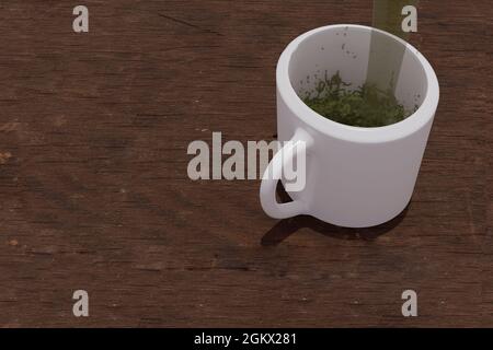Green tea Matcha served by jet between steam and water splashes entering transparent white cup on rustic wooden table in Mexico Stock Photo