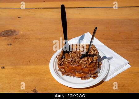 Sticky caramel roll with nuts, two forks for sharing food or dessert concept. Taken outside on picnic table Stock Photo