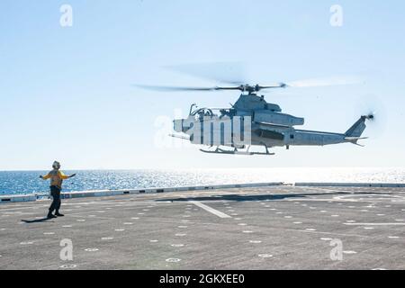 210718-N-XB010-1021 CORAL SEA (July 18, 2021) Aviation Boatswain’s Mate (handling) 3rd Class Jake Angulo, from Riverside, Calif., guides a U.S. Marine Corps AH-1Z Cobra helicopter as it takes off from the USS New Orleans (LPD 18) flight deck in preparation for the arrival of Capt. Greg Baker, Commodore, Amphibious Squadron 11, and Col. Michael R. Nakonieczny, commanding officer of the 31st Marine Expeditionary Unit (MEU). New Orleans, part of the America Expeditionary Strike Group, along with the 31st MEU, is operating in the U.S. 7th Fleet area of responsibility to enhance interoperability wi Stock Photo