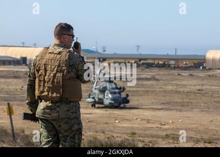 U.S. Marine Corps Gunnery Sgt. Stephen Leskoven, a bulk fuel specialist with Marine Wing Support Squadron 372, 3rd Marine Aircraft Wing (MAW), utilizes a radio to communicate with the pilots of the CH-53E Super Stallion to land at a forward arming and refueling point (FARP) that has been established on San Clemente Island, July 20, 2021. During Advanced Naval Basing evolution of Summer Fury 21, 3rd MAW established a FARP on the existing airfield to increase the range and tempo of aviation operations within the area of responsibility to evaluate the operational capability for application in fut Stock Photo