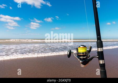 Fishing rod with fishing reel on the beach on a beautiful sunset. Vertical  photo Stock Photo - Alamy