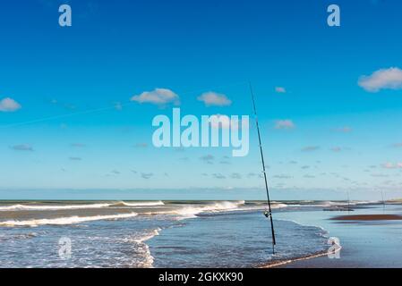 Fishing rod with fishing reel on the beach on a beautiful sunset. Vertical  photo Stock Photo - Alamy