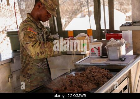 Spc. Courtney Roseborough, assigned to Regimental Support Squadron, 11th Armored Cavalry Regiment, seasons a lunch entree at the field feeding site, National Training Center and Fort Irwin, Calif., July 20th, 2021. He is part of the 11th Armored Cavalry Regiment field feeding team representing the National Training Center for the Philip A. Connelly Active Army Kitchen Competition. Stock Photo