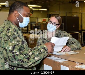JACKSONVILLE, Fla. (July 23, 2021) - Happy 74th birthday, Navy Medical Service Corps!  Lt.j.g. Amanda Rabbitt discusses medical supply destinations with Retail Services Specialist 3rd Class Dvonte McGhee at Naval Hospital Jacksonville’s warehouse.  Rabbitt, a native of Clayton, California, says, “Our staff plays a critical role in facilitating the timely, accurate, and reliable delivery of goods and services to provide top-quality care to patients.”  Since Aug. 4, 1947, the Medical Service Corps has led from the front in clinical, scientific, and administrative specialties, while supporting th Stock Photo