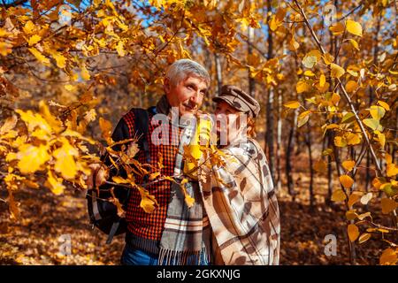 Fall season. Senior family couple walking in autumn park. Happy middle-aged man and woman hugging and relaxing outdoors. Stock Photo