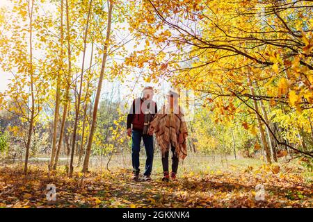 Fall season walk. Senior family couple walking in autumn park. Happy man and woman spending time together outdoors Stock Photo