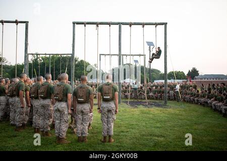 U.S. Marine Corps officer candidates with Lima Company receive instructions on proper rope climbing techniques from Officer Candidate School (OCS) staff before participating in the obstacle course at OCS on Marine Corps Base Quantico, Virginia, July 22, 2021. The purpose of the Obstacle Course is to test the candidate’s ability to negotiate obstacles using the correct techniques while displaying a high level of agility, muscular strength, and stamina. Stock Photo