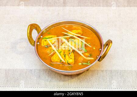 Indian chicken curry recipe with vegetables and fresh coriander chopped in a traditional metal bowl Stock Photo