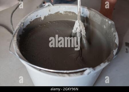 Mixing concrete in bucket for floor repairing. Stock Photo