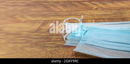 Disposable surgical mask. Stack of surgical masks on wooden table. Blue medical mask. Medical protective masks on wooden background. Stock Photo