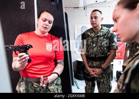 Lt. Kyrie Slade, a class officer assigned to Officer Training Command, Newport (OTCN), Rhode Island, explains the firing sequence of the M9 pistol to Officer Candidate School (OCS) class 14-21 students during a small arms qualification, July 27. OCS develops civilians and fleet Sailors into newly commissioned officers morally, mentally, and physically and imbues them with the highest ideals of honor, courage and commitment for service in the fleet as Naval officers. Stock Photo