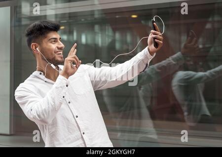 Young man smiling happy doing video call using smartphone at city. High quality photo Stock Photo