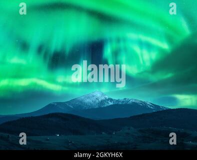 Aurora borealis over the snow covered mountain peak in europe Stock Photo