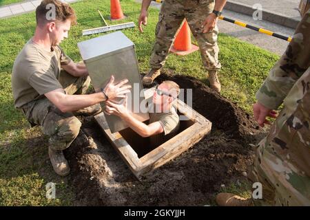 Airman 1st Class Trey Adley, left, and Senior Airman Jonathan Stroh, 374th Civil Engineer Squadron pavement and equipment operators, bury a time capsule at Yokota Air Base, Japan, July 29, 2021. The 374th CES members placed the time capsule in a hole roughly six feet deep to be closed until the next iteration of Summer Olympic Games in Japan. Stock Photo