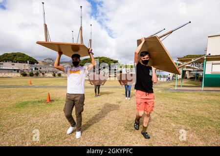 U.S. Marines with Headquarters Battalion, Marine Corps Base Hawaii, carry desks to another classroom during a volunteer event at Kailua Elementary School, Hawaii, July 30, 2021. MCBH’s most important resource is people, partnering with and supporting the local community is among the installation’s top priorities. Stock Photo