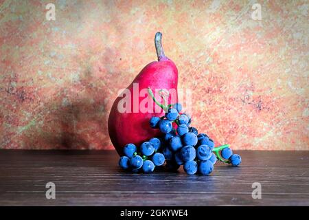 Stilll life of a red pear and grapes with a rustic background Stock Photo