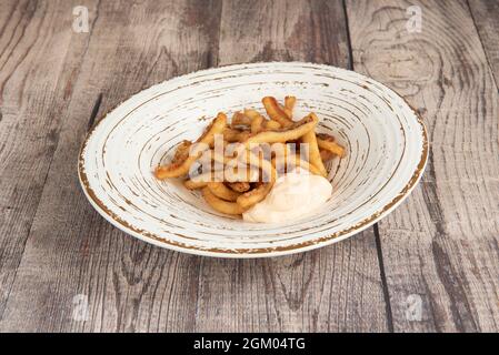 Spanish tapa of squid rabas in batter with aioli sauce tear on wooden table Stock Photo