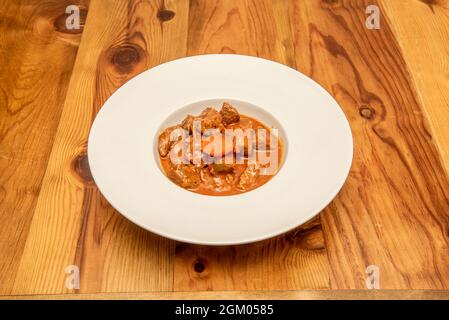 Plate of stewed beef ragu with vegetables on wooden table Stock Photo