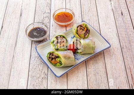 Fried Roast Duck Rolls with Lettuce, Carrots, Zucchini, Cherry Tomatoes and Dipping Sauces Stock Photo