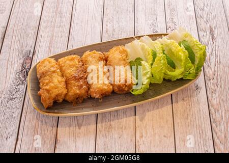 Crispy breaded Vietnamese nems rolls stuffed with chicken and prawns with heart leaves Stock Photo