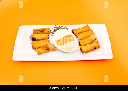 serving of crispy Chinese spring rolls fried in olive oil and various dipping sauces Stock Photo