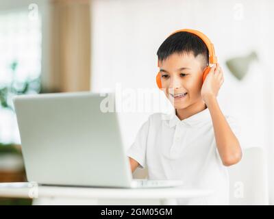 Boy wearing headphones and studying online with laptop. Stock Photo