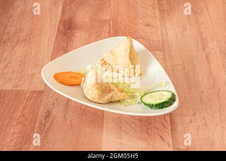 Vegetable samosas cooked in Pakistani kebab restaurant with white plate in Ramadan and wooden table Stock Photo