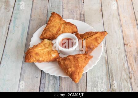 Vegetable samosas fried in oil with sauce in the center to dip Stock Photo