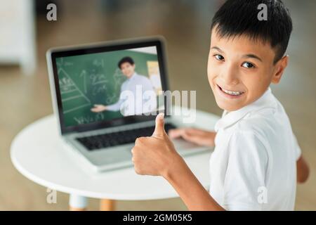 Boy study online with laptop.Looking at camera and showing thumb up. Stock Photo