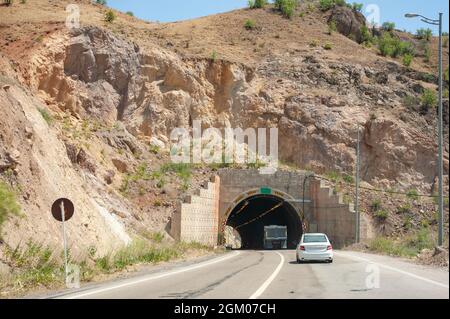 Motorway two way tunnel entrance in the mountain with car in frame, warning signs in kurdistan province, iran Stock Photo