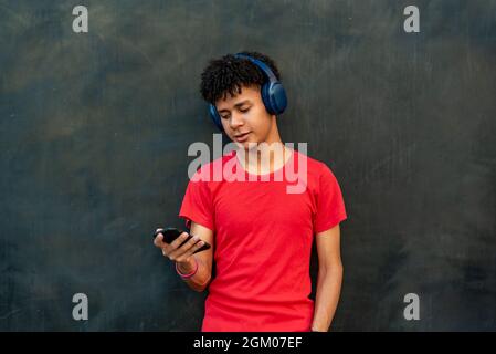 Afro latin young man listening to music against a wall Stock Photo