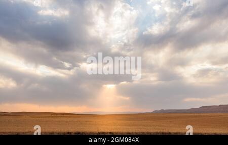 harvested Wheat field with partly cloudy sky with sunlight passing through in Kurdistan province, iran Stock Photo