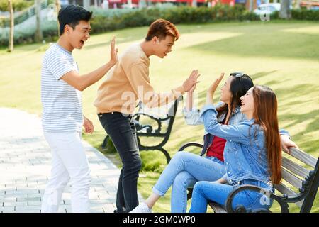Excited fellow students giving high five happy to see each other after summer vacation Stock Photo