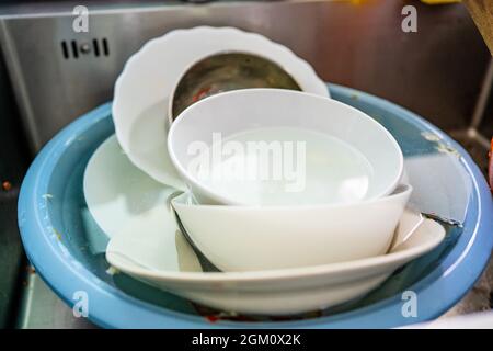 Used dishes prepared to wash on the kitchen sink Stock Photo