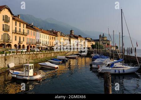 View of Cannobio, its harbour, boats and reflections soon after sunrise on Lake Maggiore in Piedmont, Italy Stock Photo